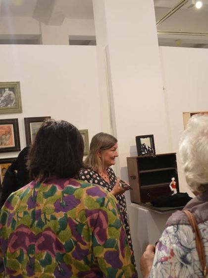 Visitors examining a display case with small sculptures and memorabilia as part of the 'Southern Stars' exhibition.