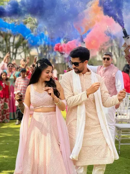 The couple dancing amidst colorful smoke bombs. The bride's pink lehenga and soft glam makeup create a picture-perfect moment.