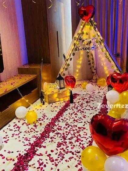 A romantic proposal or anniversary setup in a living room space. I created a pathway of rose petals leading to a cozy cabana tent decorated with fairy lights, heart-shaped balloons, and lanterns.