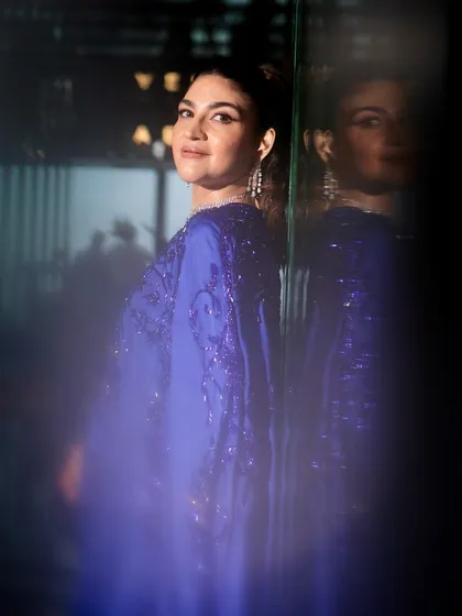 An artistic and moody shot of the royal blue cape saree look. The makeup remains a focal point, with a glamorous and elegant feel.