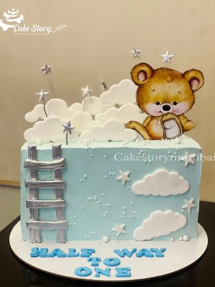 A 'Half Way to One' cake for a six-month celebration. The square cake features a cute bear climbing a ladder to the stars, marking the halfway point to the first birthday.