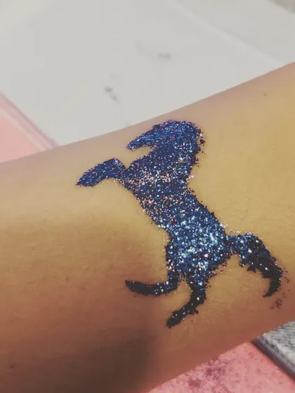 The classic unicorn silhouette is a timeless favorite. This deep blue glitter tattoo is bold and sparkly, perfect for any guest who loves these mythical creatures.