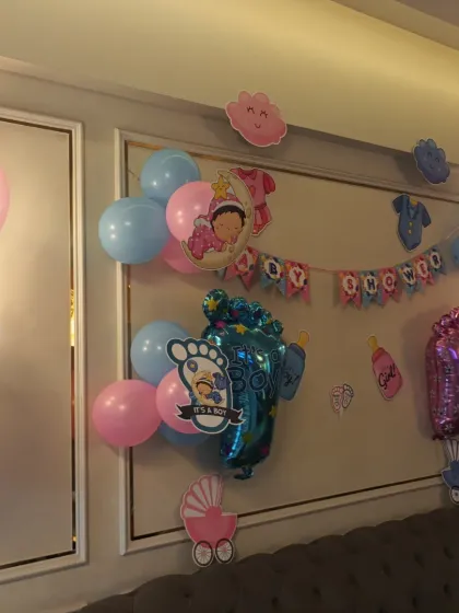 A wider view of the baby shower wall decoration, showing the placement of pink and blue balloons to match the theme.