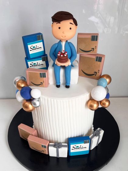 Turning milestones into memories. This corporate cake features a custom figurine and is surrounded by branded boxes and Amazon packages, telling the story of a colleague's journey.