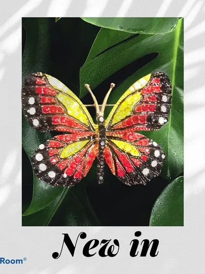 A new-in butterfly brooch with vibrant red and yellow wings, set against a green leaf. This piece is perfect for adding a pop of color and nature-inspired beauty to your look.