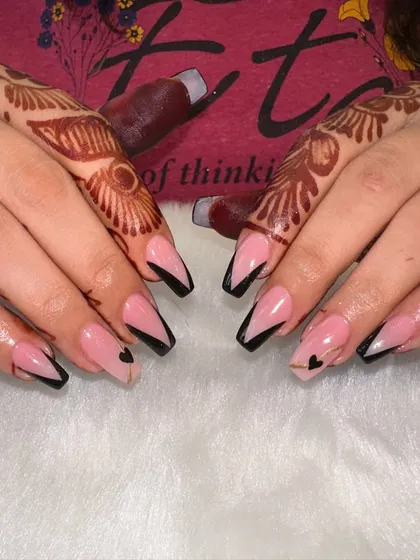 A modern French with a touch of love. This design uses a sharp, black V-shaped tip on a sheer pink base, with a tiny, delicate gold heart accent for a subtle and stylish detail.