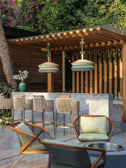 Another angle of the outdoor bar and fire pit lounge, highlighting the durable, weather-resistant furniture made from acacia wood and wicker.