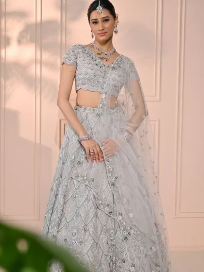 A full-length portrait of the modern bride. The intricate silver lehenga is the centerpiece, with the makeup providing a soft, elegant frame for her beauty.