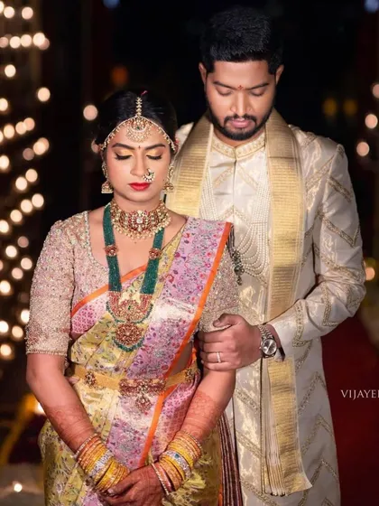 A regal couple portrait. The bride's fully embroidered gold blouse pairs beautifully with her multi-toned pastel saree and emerald jewelry.