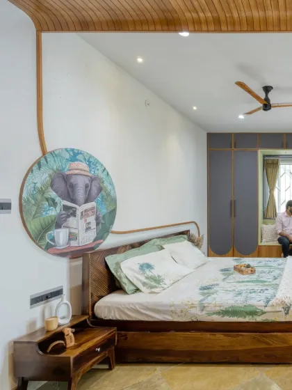 A master bedroom designed as a serene retreat. We used a custom-designed teak wood bed with an integrated art piece and a bay window seat to create a space that is both restful and full of personality, grounded by natural Kota stone flooring.