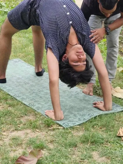 Taking our practice outdoors connects us with nature. Here, one of our members works on his backbend flexibility with the assistance of an instructor.