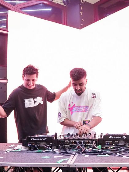 A candid moment during a B2B set, with both DJs focused on the music.