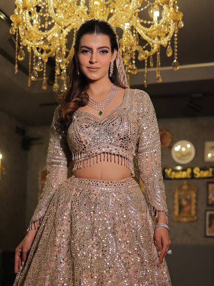 A trending mirror-work lehenga that catches the light beautifully. This shot under a chandelier highlights the incredible sparkle and craftsmanship.