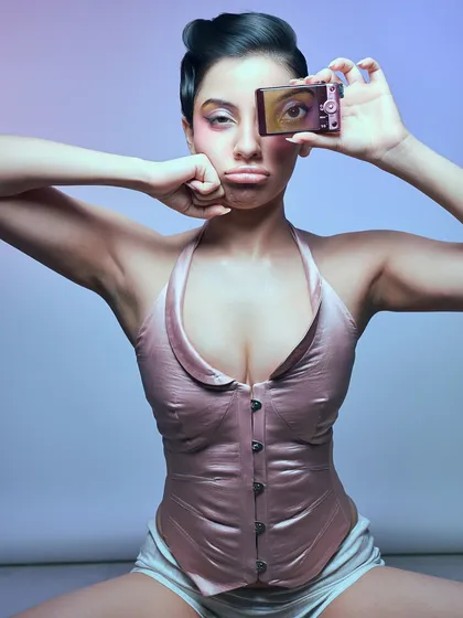 A playful and slightly rebellious portrait questioning the nature of art. The model holds a digicam, creating a meta-commentary on image-making in the digital age.