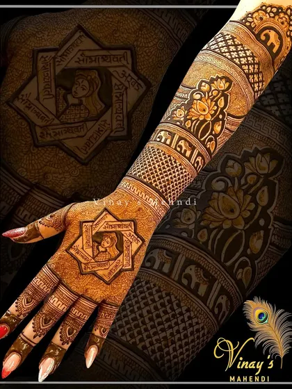 A geometric back-of-hand design with a central star-shaped frame containing a sacred symbol. The arm features lotus and elephant bands for a traditional touch.