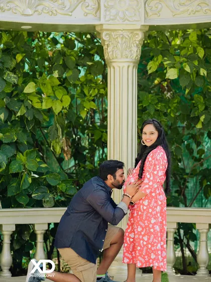 A classic romantic gesture, with the partner kissing the baby bump. This shot is taken against a beautiful white balustrade, adding a touch of elegance to a casual dress shoot.