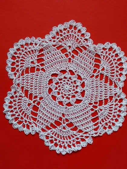 A 12-inch flower crochet doily on a red background.