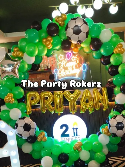 A football-themed birthday party is always a winner. This setup includes a green, black, and white balloon arch, football balloons, a neon sign, and a large light-up number '9'.