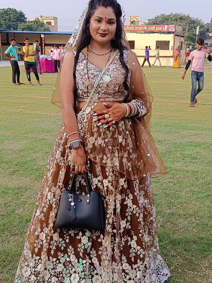 A full-length shot of the client in her brown floral lehenga, looking ready for the event with her handbag.