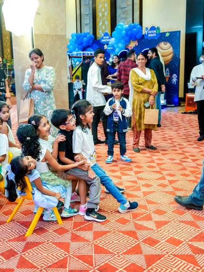 A party host and entertainer engaging a group of seated children with a captivating performance, keeping them entertained and involved.