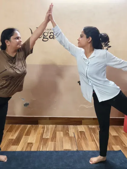 A high-five of encouragement while holding a partner Natarajasana (Dancer's Pose). This playful interaction captures the fun and supportive atmosphere of our partner yoga sessions.
