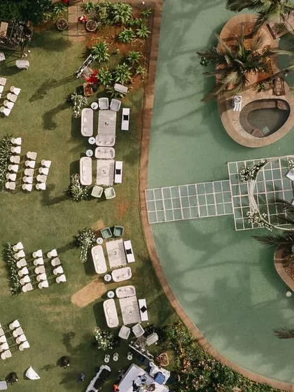 An aerial view of the complete seaside wedding layout. This perspective shows the scale of the event, with guest seating on the lawn and the central mandap perfectly positioned over the water.