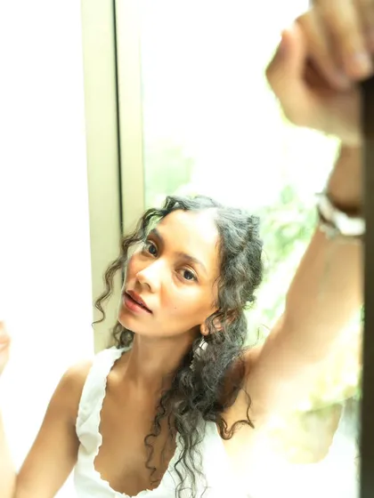 An intimate, high-key close-up. The bright light from the window creates a soft and angelic feel.