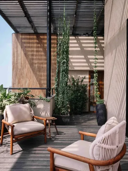 A quiet seating nook on the terrace of Project 1374. The interplay of materials like wood, woven rope, and bamboo, combined with climbing plants, creates a space that feels both crafted and natural.