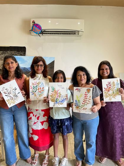A group of women and a young girl proudly display their beautiful botanical paintings on paper.