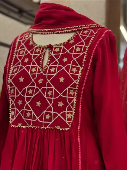 A close-up of a red velvet Anarkali with a beautifully embroidered yoke featuring a star and diamond geometric pattern.