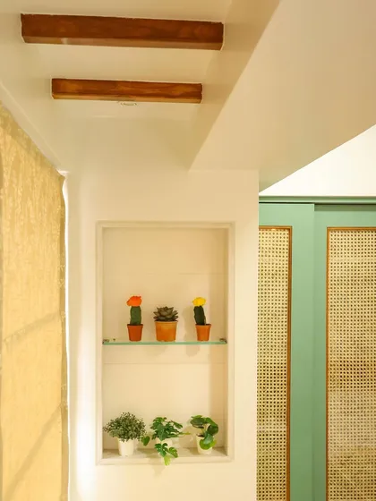 A small niche with decorative cacti adds a playful touch, complemented by the wooden beams on the ceiling.