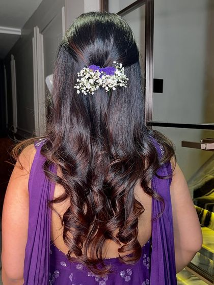 A beautiful hairstyle with soft curls and a touch of baby's breath, perfect for any festive occasion.