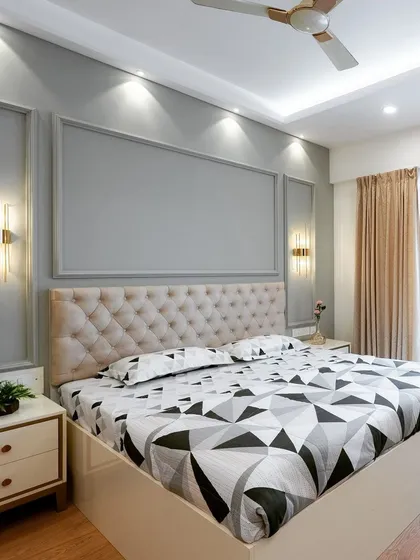 A master bedroom designed for pure relaxation. The tufted headboard adds a touch of classic comfort, while the modern wall paneling and warm accent lighting create a serene and sophisticated atmosphere.
