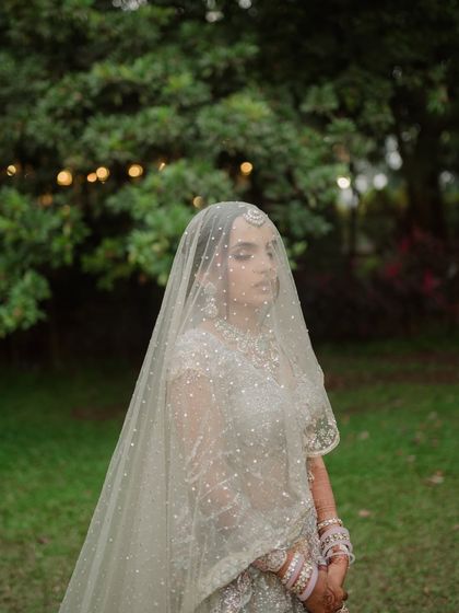 A moment of quiet contemplation under the veil. The soft, natural light and green backdrop give this portrait a serene and organic feel.