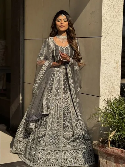 This elegant grey lehenga is a beautiful choice for a reception or engagement, proving that modern colors can be just as grand. The entire outfit is covered in intricate white threadwork and sequins, creating a shimmering, ethereal effect.