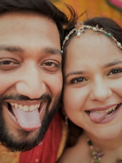 A fun, goofy close-up of a couple sticking their tongues out during their haldi ceremony.