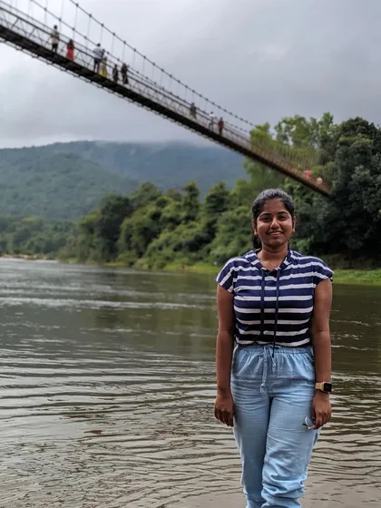A traveler posing by the river near the hanging bridge on the Netravathi trip.