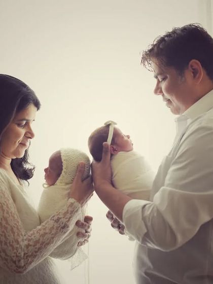 A tender moment as the parents bring their twin newborns close. These are the precious, quiet moments that tell the story of your family's beginning.