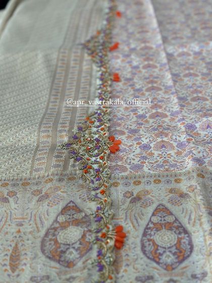 A subtle and elegant embroidered border with orange tassels on a pastel-colored printed fabric.