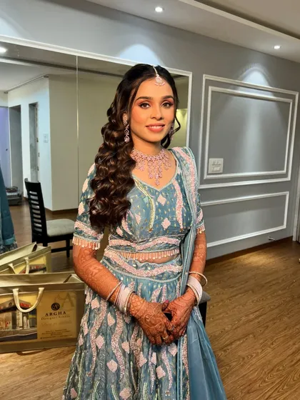 Ayushi's full engagement look, a beautiful blue and pink lehenga paired with soft, romantic curls.