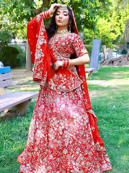 A classic red bridal lehenga with all-over floral embroidery. This timeless piece is perfect for outdoor photoshoots and is available to rent.