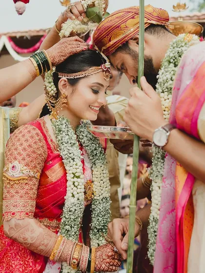 A beautiful moment from a traditional South Indian wedding. I designed this bride's classic red Kanchivaram saree blouse with intricate, heavy embroidery covering the sleeves for a regal muhurtham look.