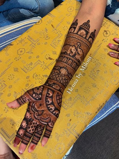 A full-arm bridal design with elephants and a name 'Shubhangi' written on the arm.