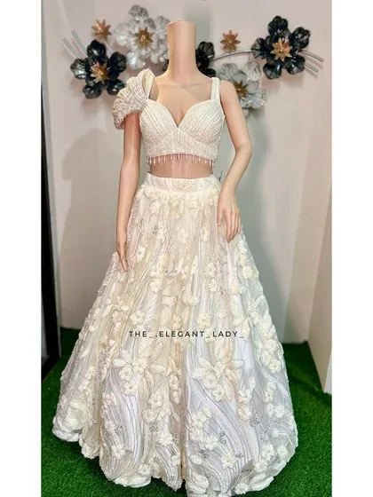 Feel like a dream in this ivory floral lehenga, perfect for a sangeet, reception, or a modern pre-wedding photoshoot. The delicate 3D floral appliqué and the unique one-shoulder blouse create a look that is both romantic and fashion-forward.