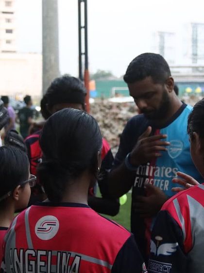 Coach Anil giving a team talk to the girls' team, providing motivation and tactical instructions before they take the field.