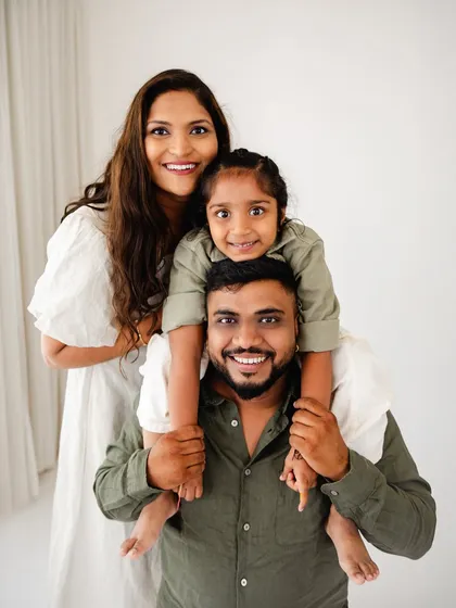 A happy family of three. This portrait showcases the fun and loving dynamic of the family, with their daughter enjoying a happy piggyback ride.