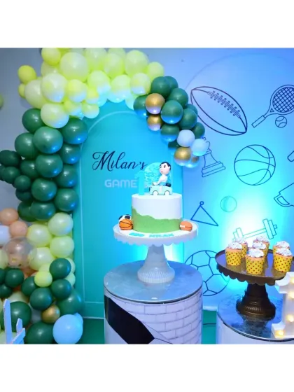 For a modern "Game On" sports theme, I used a clean, arched backdrop with line art graphics. The setup is completed with a green and peach balloon garland and a matching cake table.