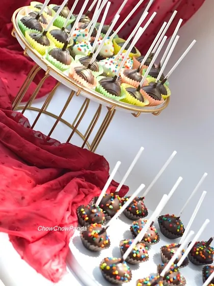 Here is a large order of cake pops ready for a party dessert table. This set includes a variety of chocolate-dipped pops, some with colourful sprinkles and others with a simple chocolate drizzle.