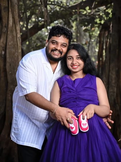 A joyful couple's portrait for their maternity announcement. The vibrant purple gown and tiny baby shoes make for a heartwarming and colorful memory.