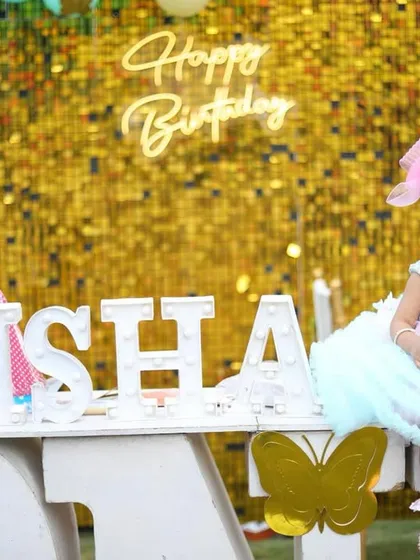 For this little girl's first birthday, I made sure to capture her with the beautiful decorations. This wide shot shows the full setup, from the custom light-up name sign to the golden sequin backdrop, making for a perfect memory of her special day.